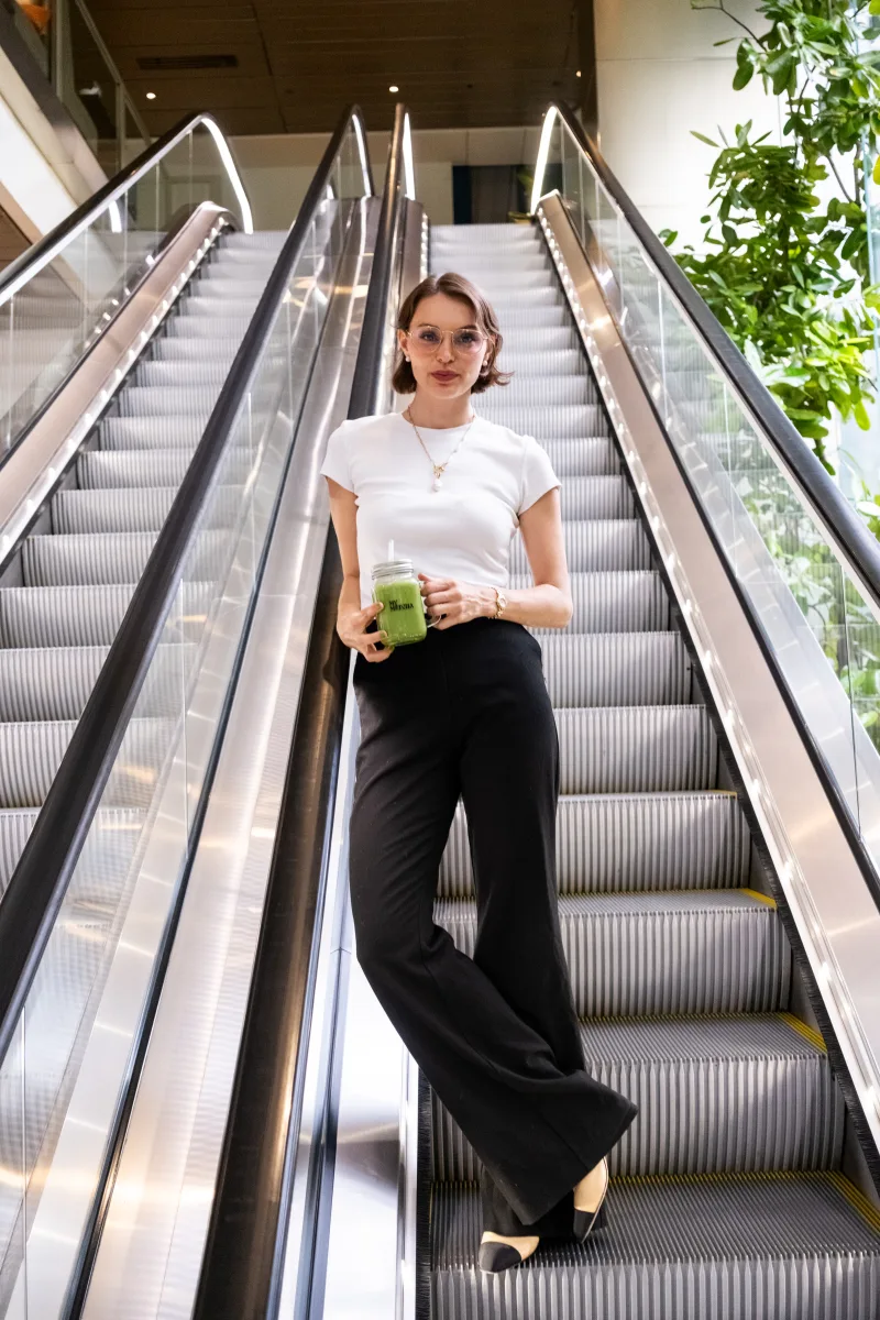 Woman heading up an escalator with a MyMatcha jar in hand