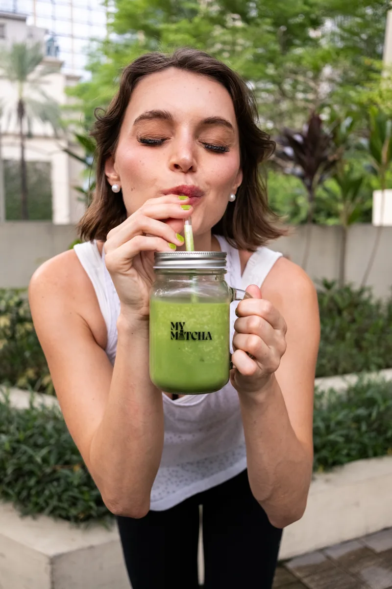 Woman sipping a bright green MyMatcha drink outdoors